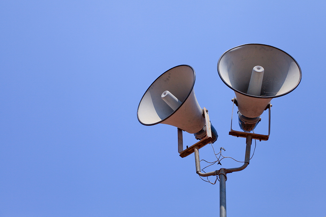 Two megaphones/speakers in front of a clear blue sky